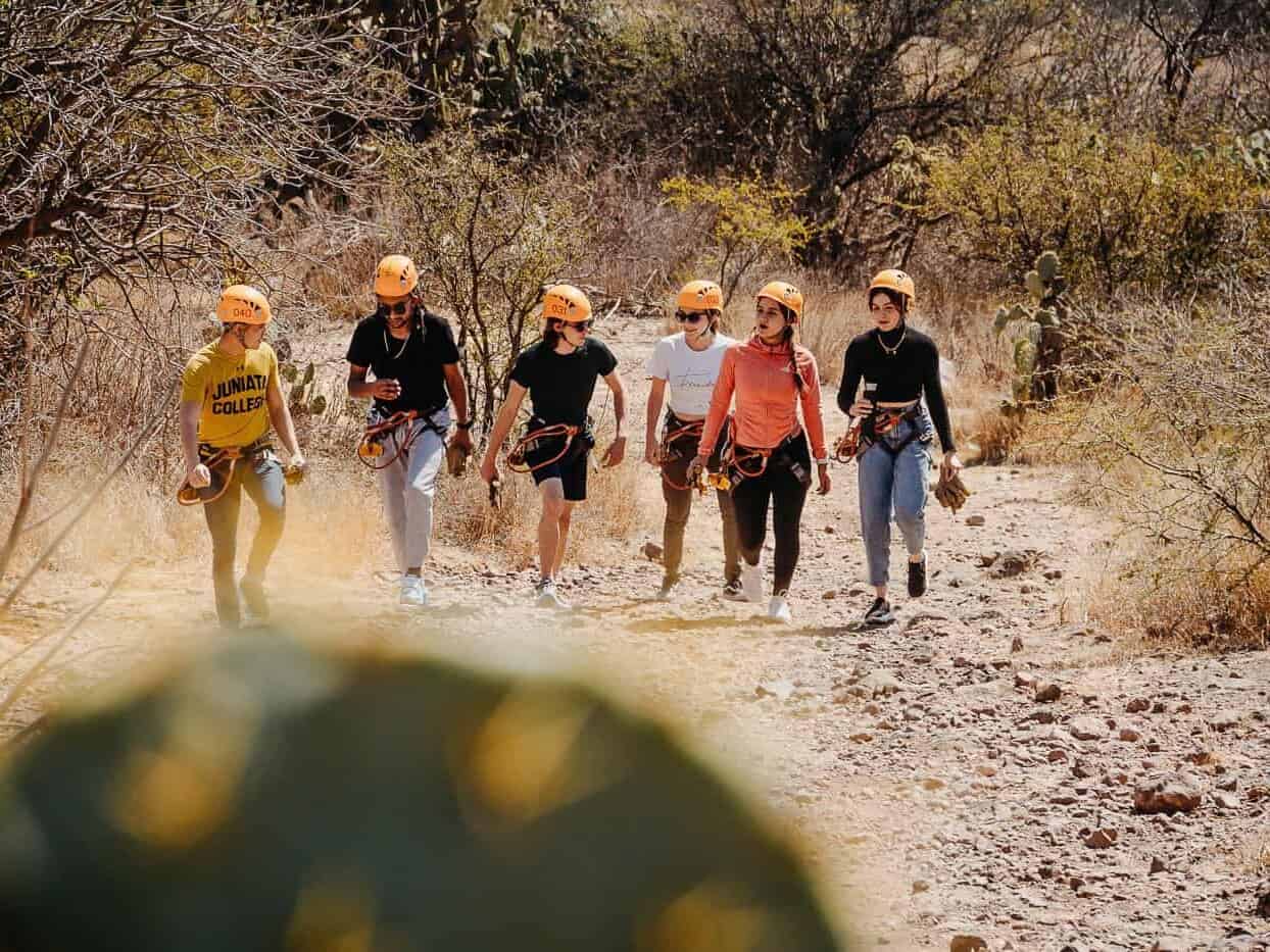 Grupo con cascos caminando por un sendero entre matorrales.