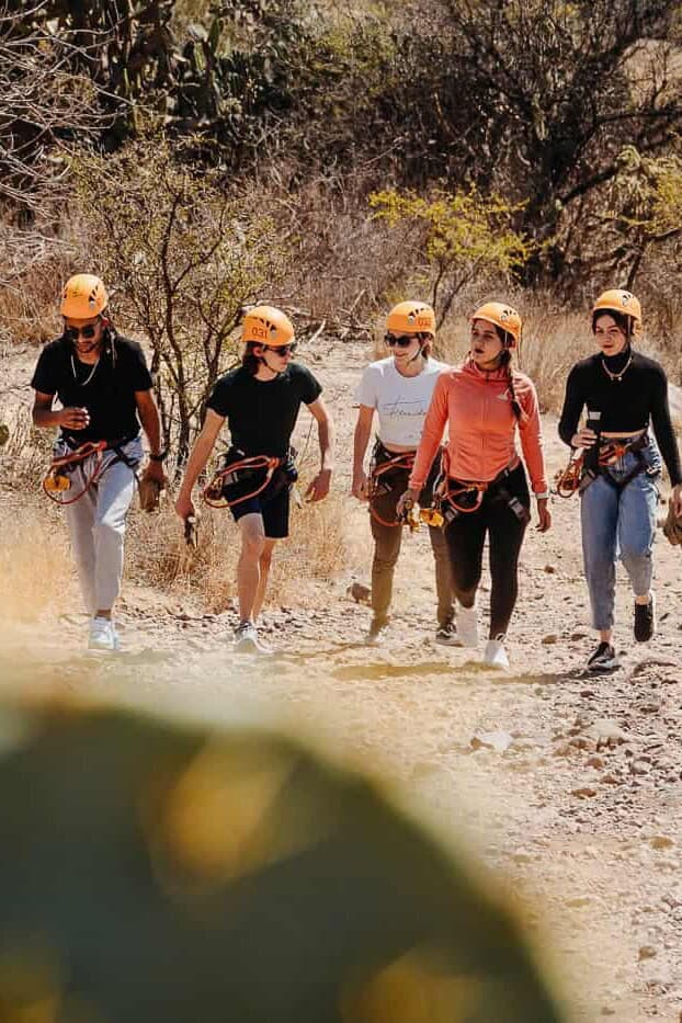 Group with helmets walking along a path through brush.
