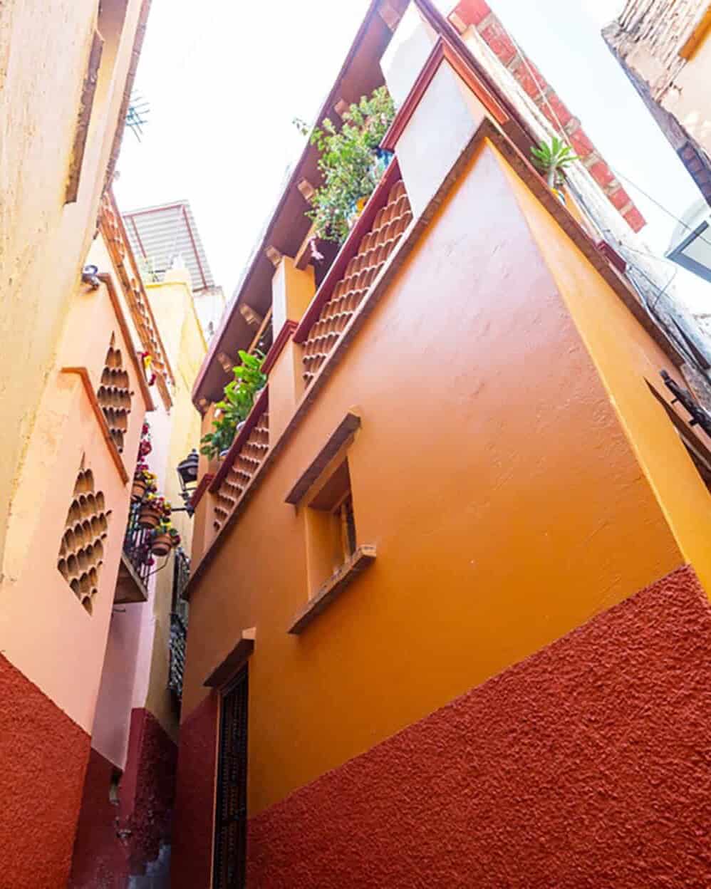 Callejón pintoresco en Guanajuato con casas coloridas y balcones floridos.
