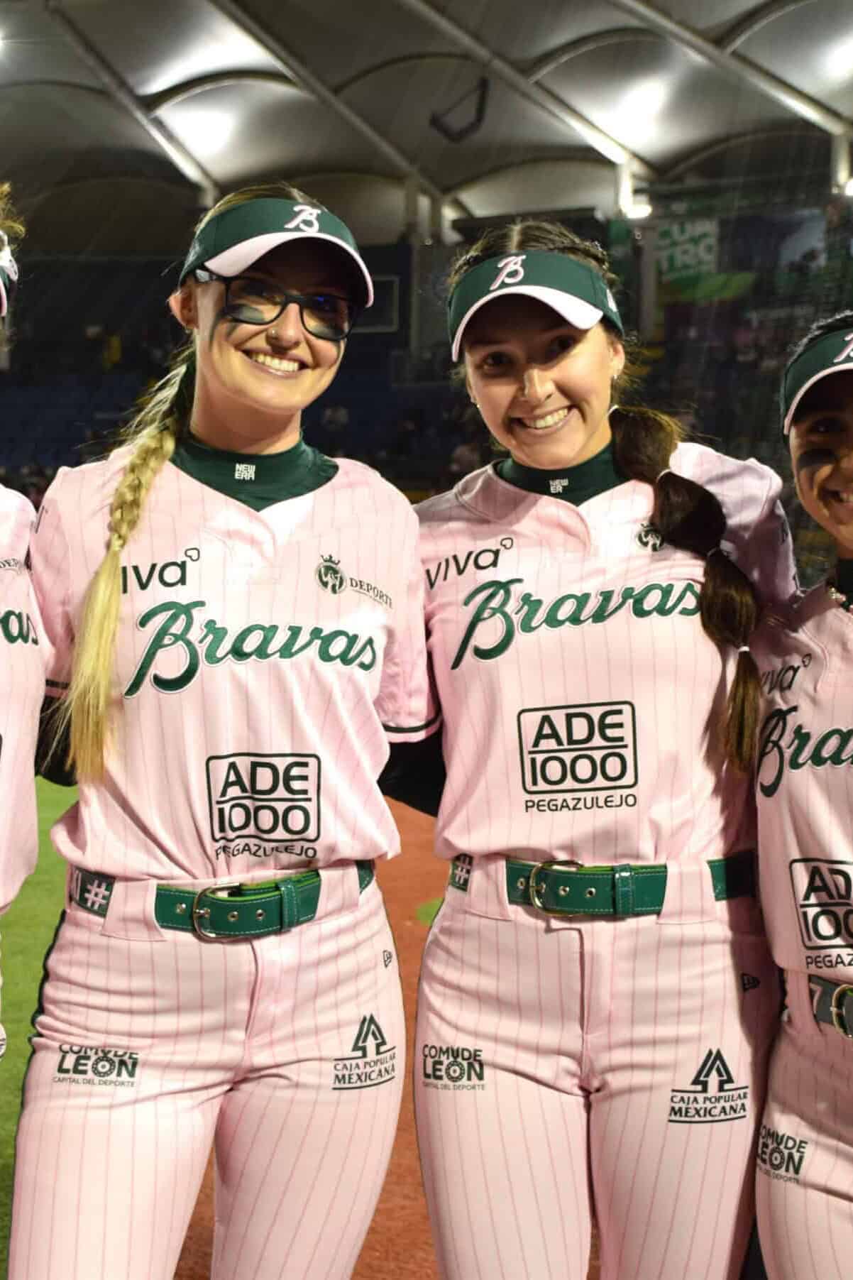 Equipo femenino de béisbol en Guanajuato luciendo uniformes rosas en evento deportivo.