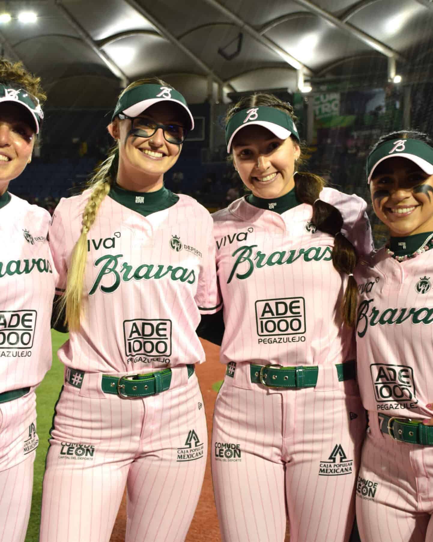 Equipo femenino de béisbol en Guanajuato luciendo uniformes rosas en evento deportivo.