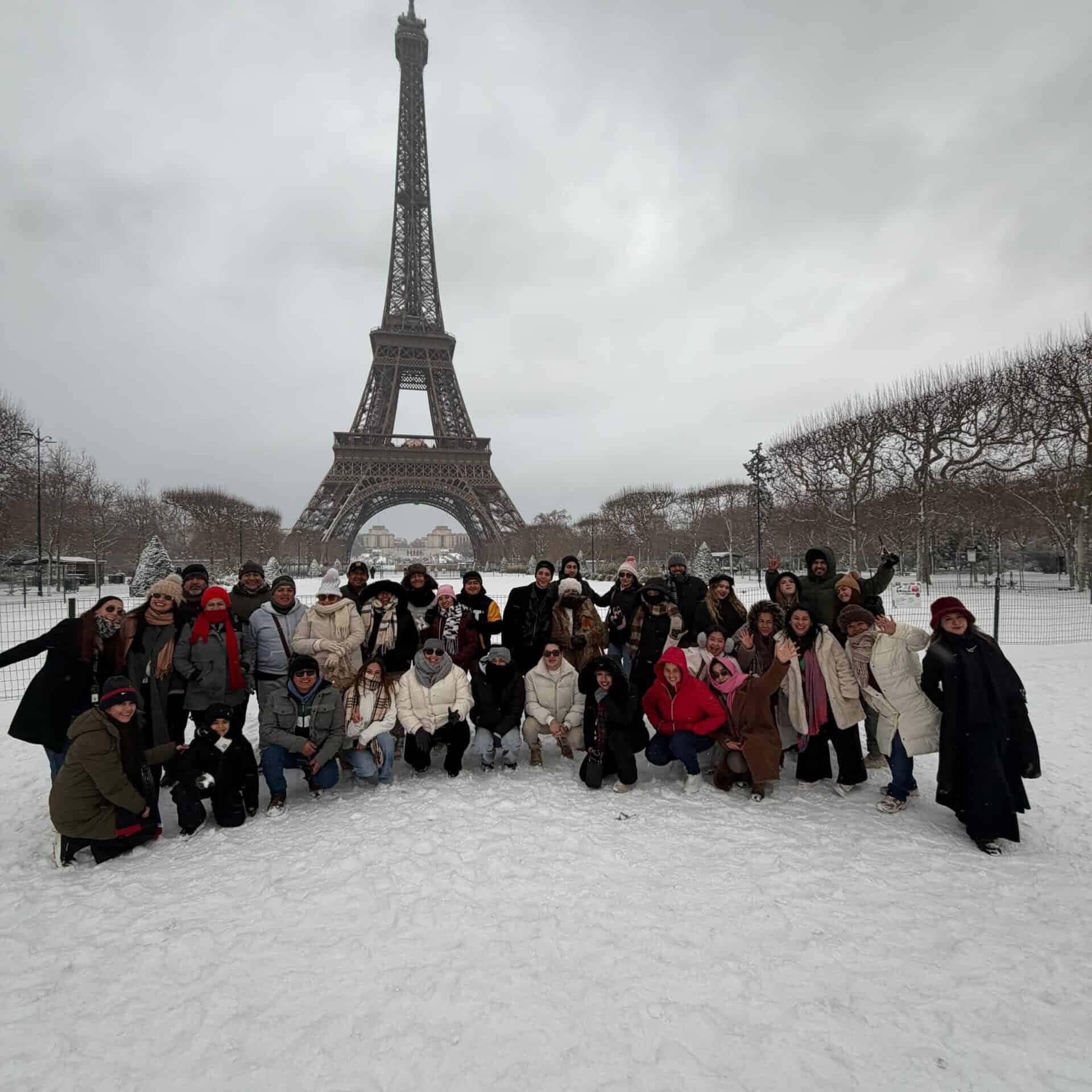 Grupo de turistas en París con la Torre Eiffel de fondo en un día nevado.