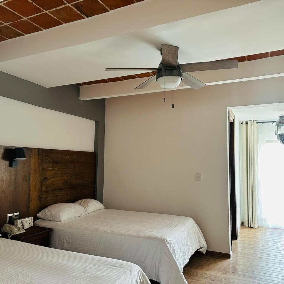 Habitación moderna en Hotel La Mansión, Guanajuato, con camas cómodas y decoración elegante.