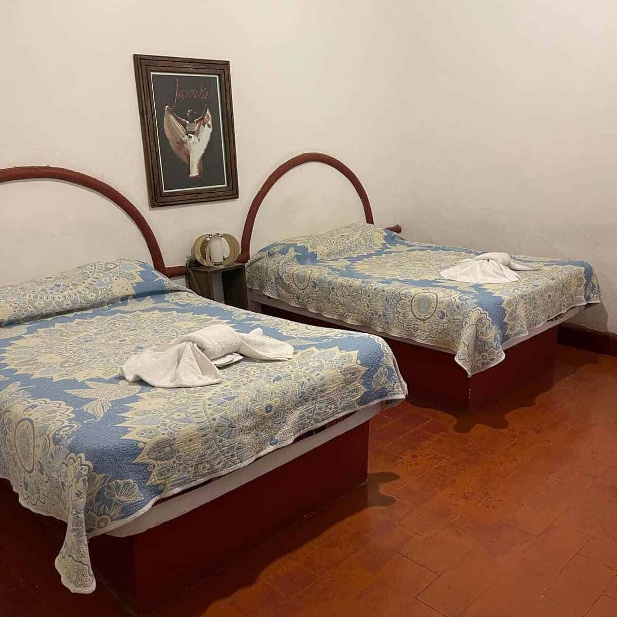 Room with two beds in a Guanajuato hotel, with simple bedding and decor.