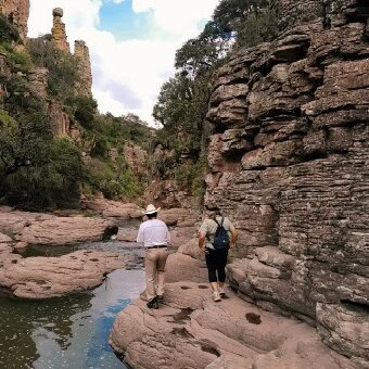 Turistas explorando un cañón con formaciones rocosas y río en Guanajuato, México.