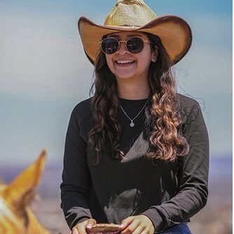 Mujer sonriendo con sombrero y gafas en parque ecoturístico en San Miguel.