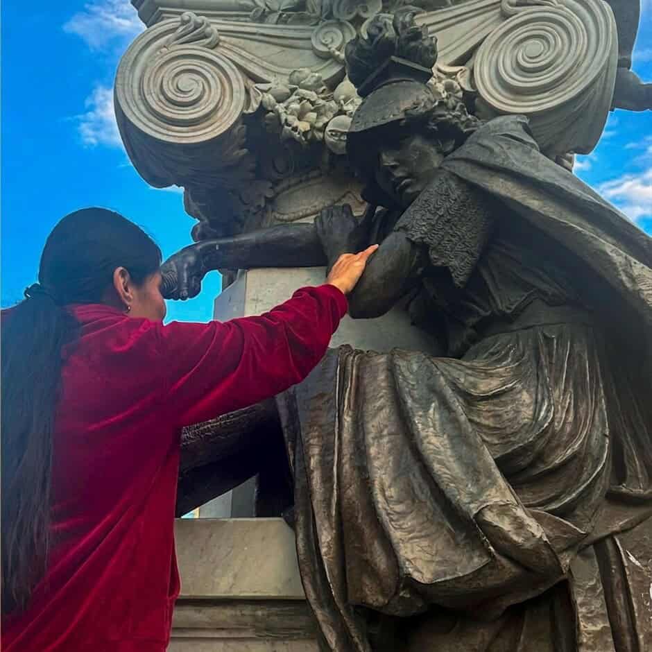 Persona limpiando una escultura en Guanajuato, México, en un día soleado.