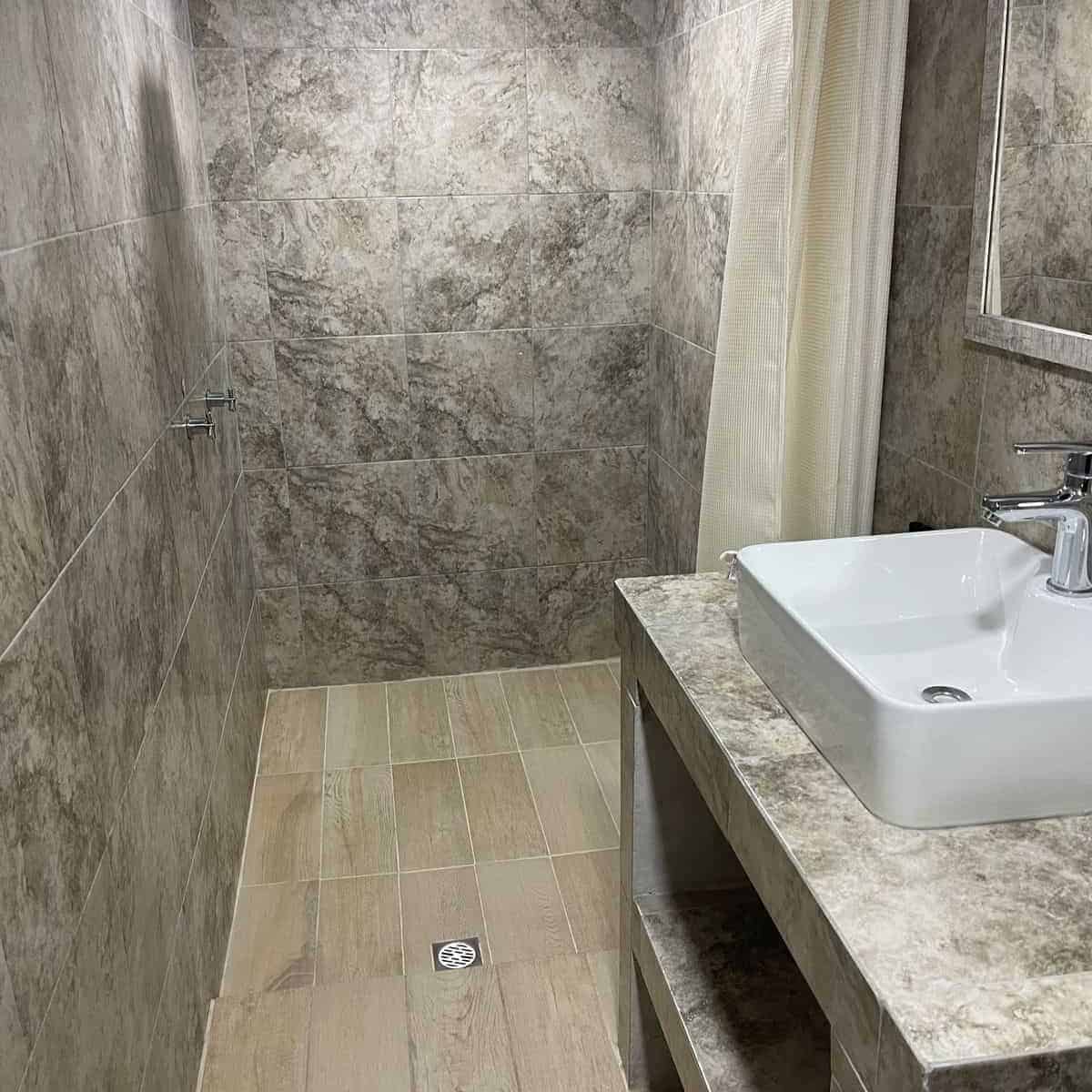 Lavatory and shower in a contemporary style bathroom in Guanajuato, with stone finishes and tile.