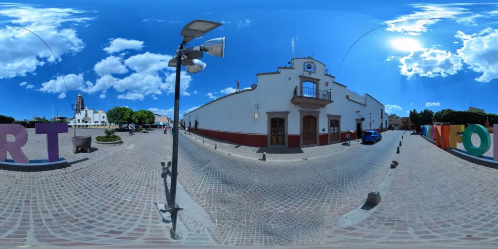 Vista 360° de la plaza principal de Comonfort, Guanajuato, con las letras monumentales del municipio frente a un edificio colonial con reloj.