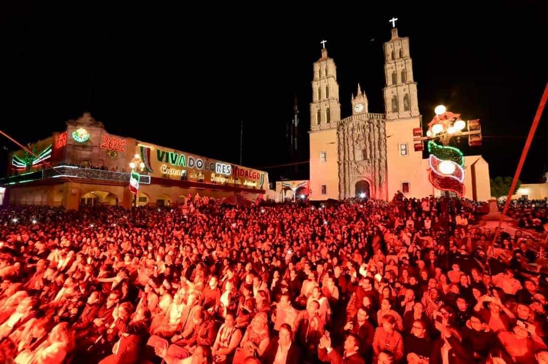 Multitud disfrutando de una fiesta en Guanajuato con la catedral iluminada de fondo.