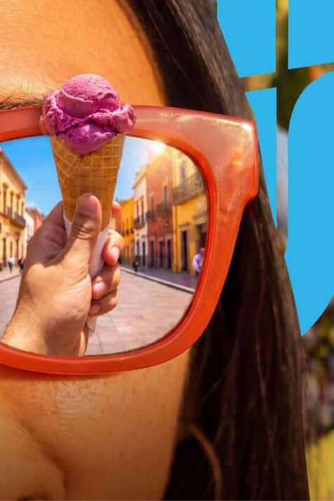 Mujer con gafas de sol reflejando calles de Guanajuato en verano.