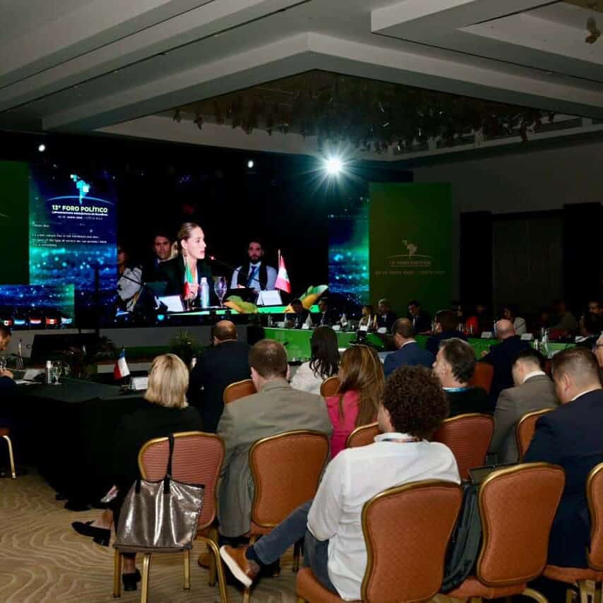 El evento político en un salón de conferencias con audiencia atenta y pantallas grandes mostrando la.