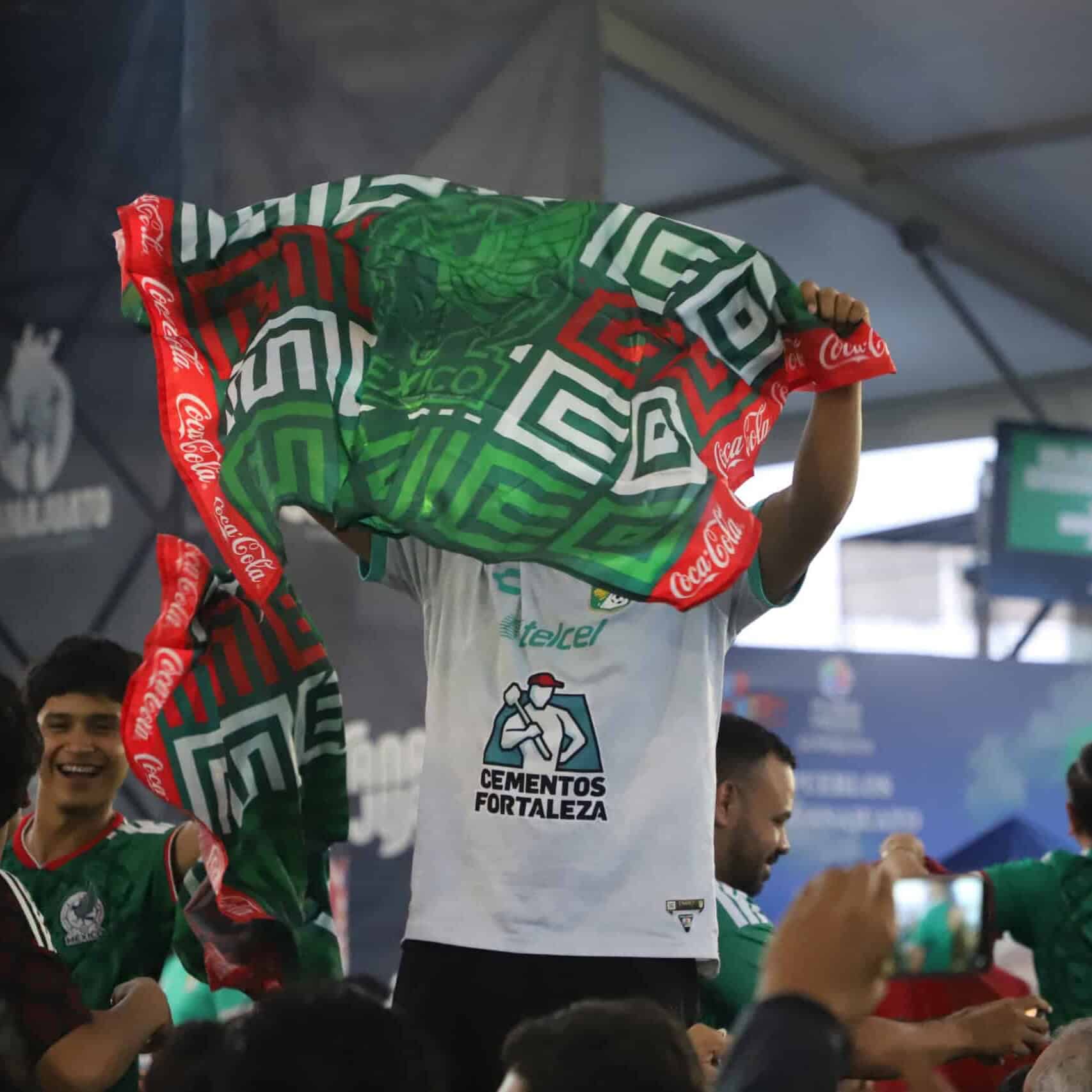 Aficionados celebran con banderas de México en un evento deportivo.