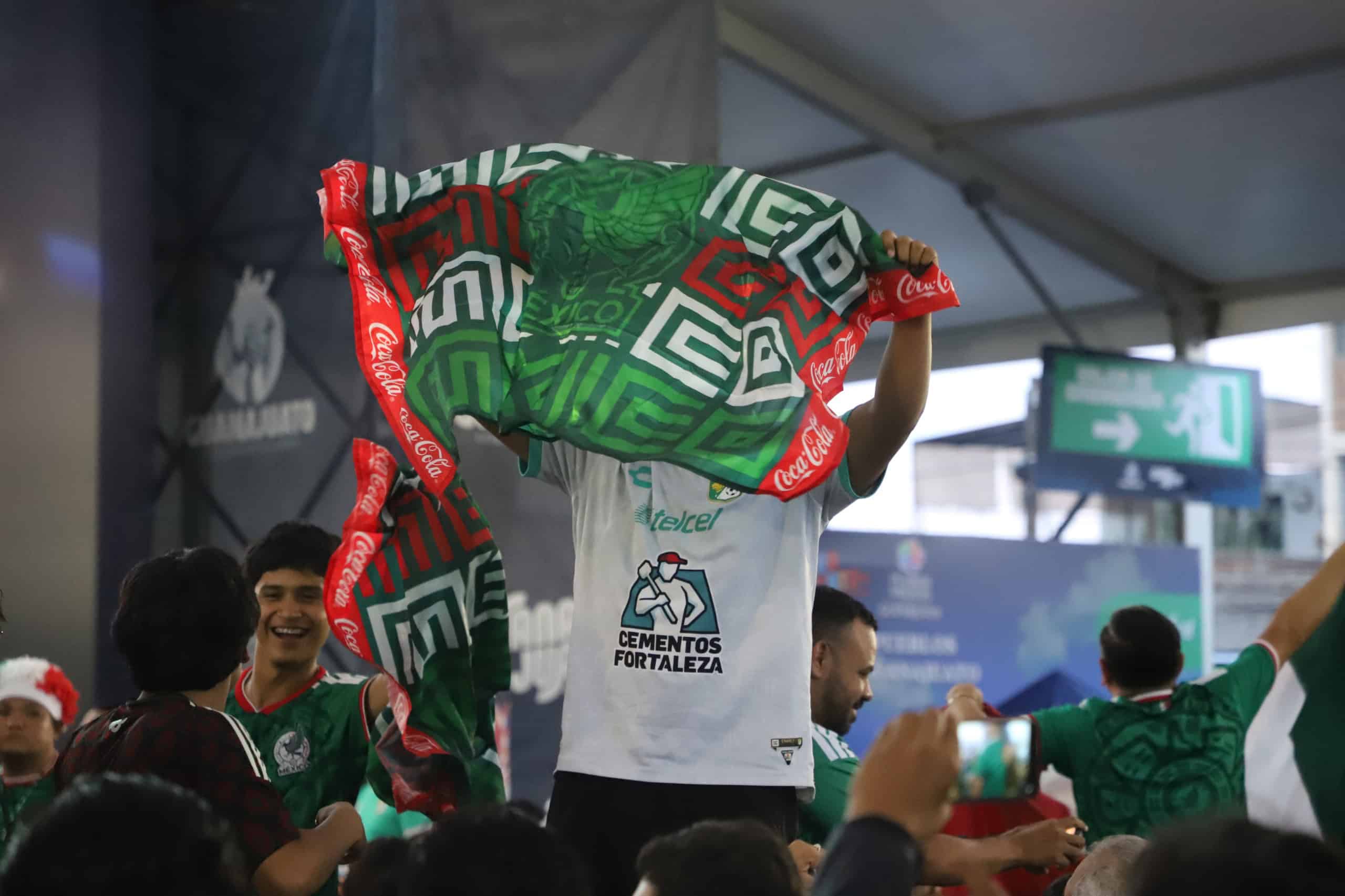 Aficionados celebran con banderas de México en un evento deportivo.