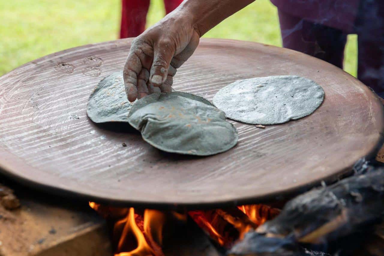 Persona colocando masa en piedra caliente para hacer tortillas tradicionales en Guanajuato, M&eacute;xico.