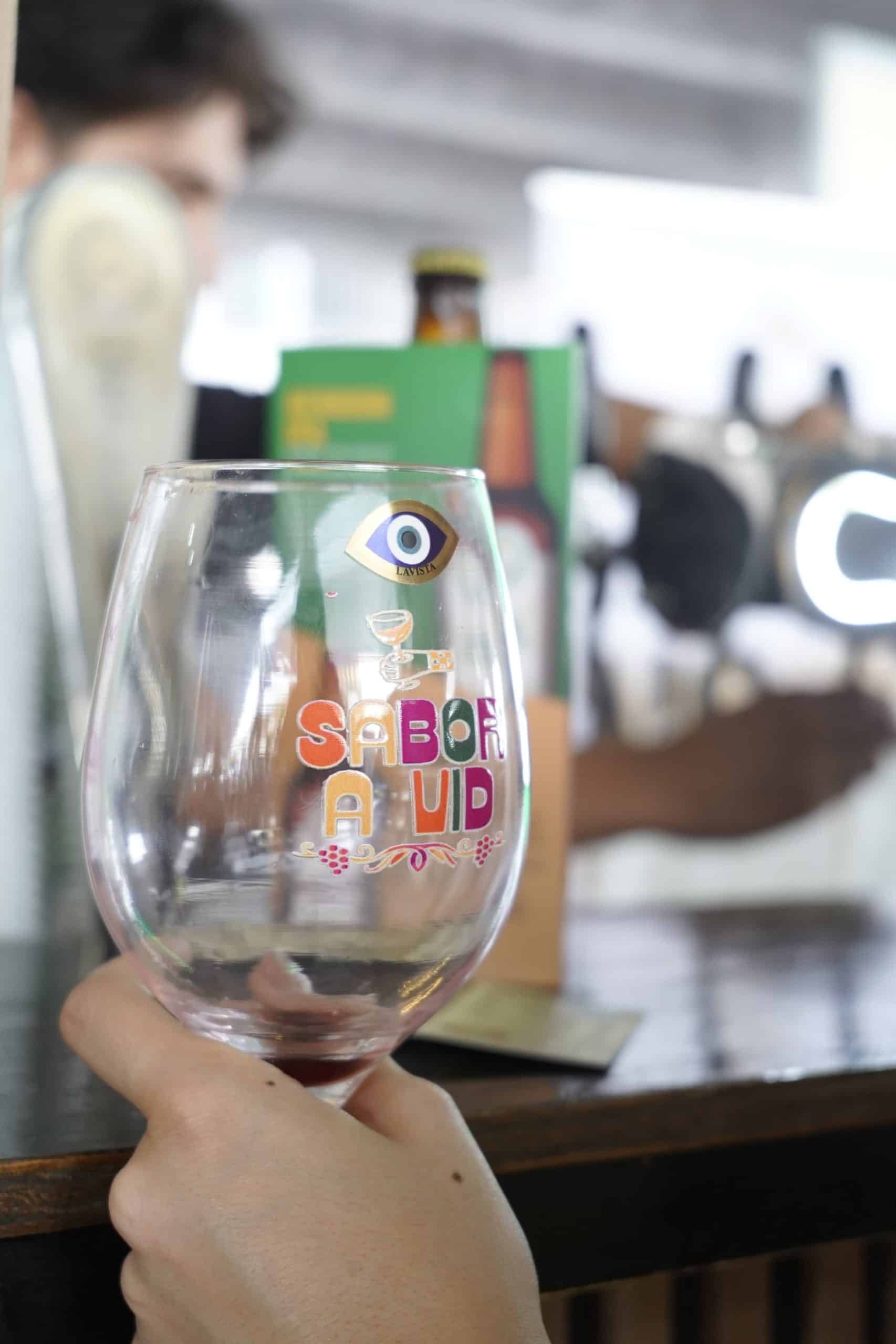 Vaso de cristal con dise&ntilde;o colorido y texto en espa&ntilde;ol, en un ambiente de bar o restaurante en Guana.