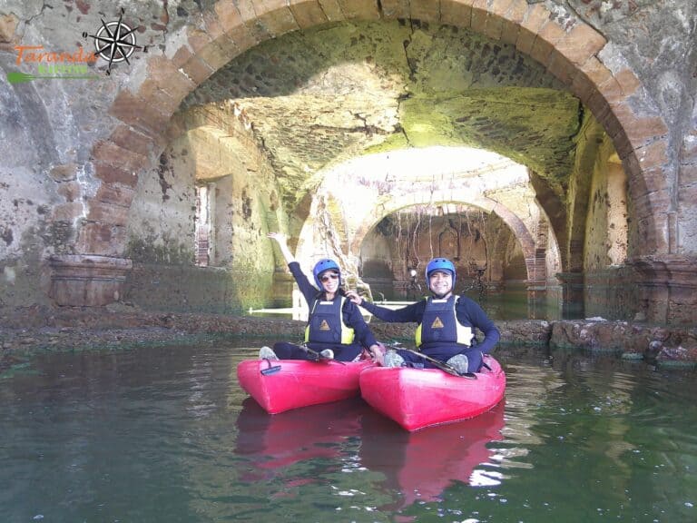 Dos personas en kayak en un río bajo un puente antiguo en Guanajuato, México.
