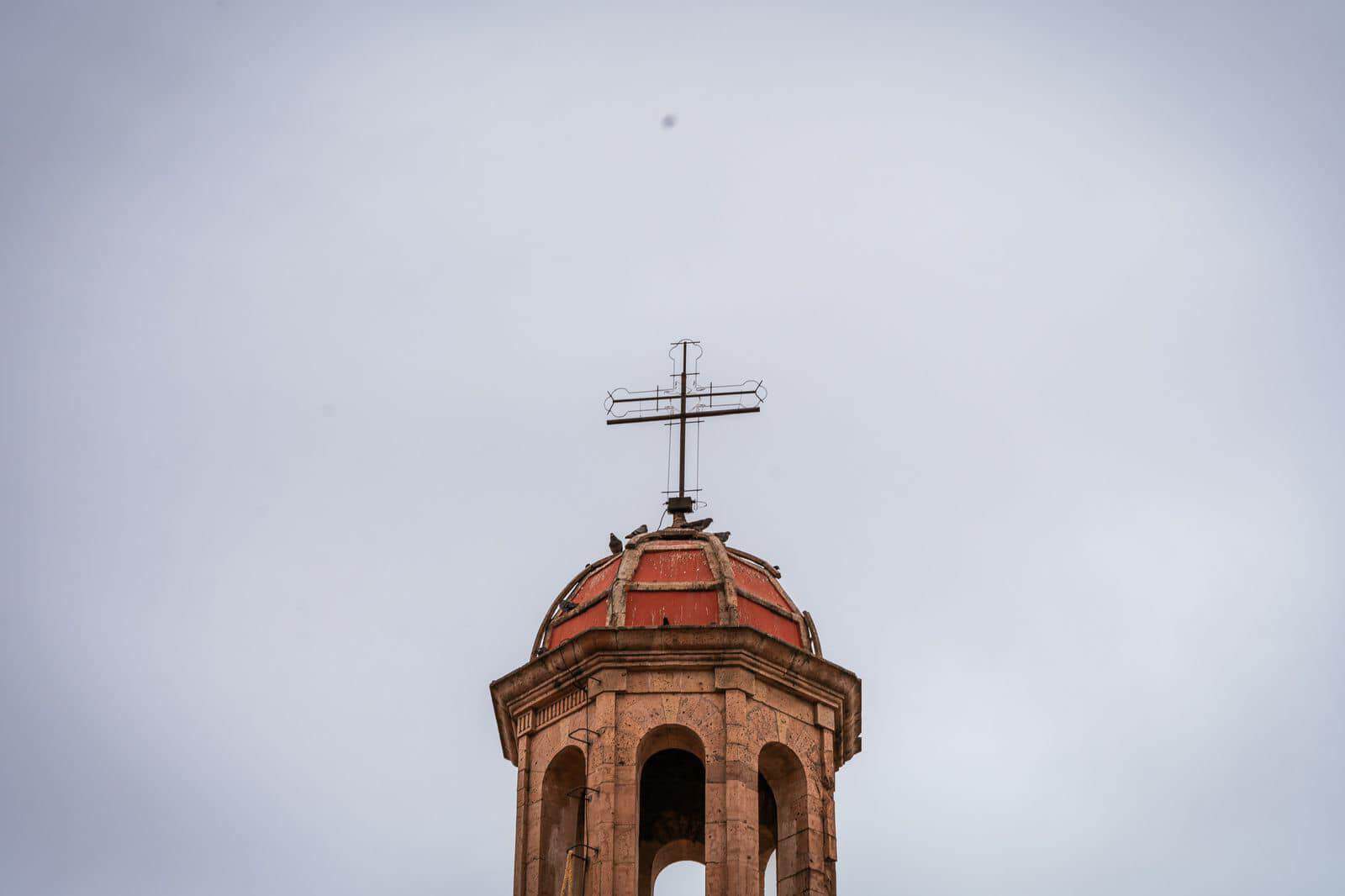 Campanario de color terracota en un cielo nublado en Guanajuato.