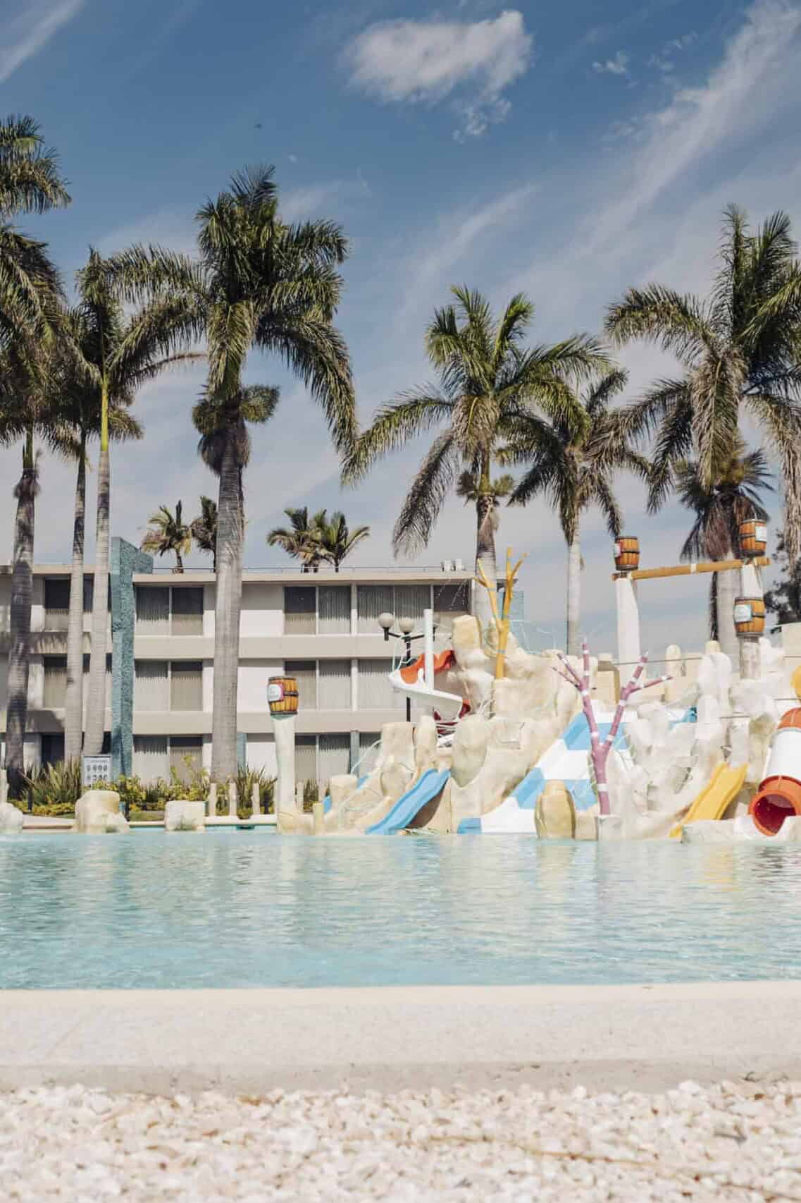 Piscina con toboganes y palmeras en Hotel y Parque Acuático La Caldera.