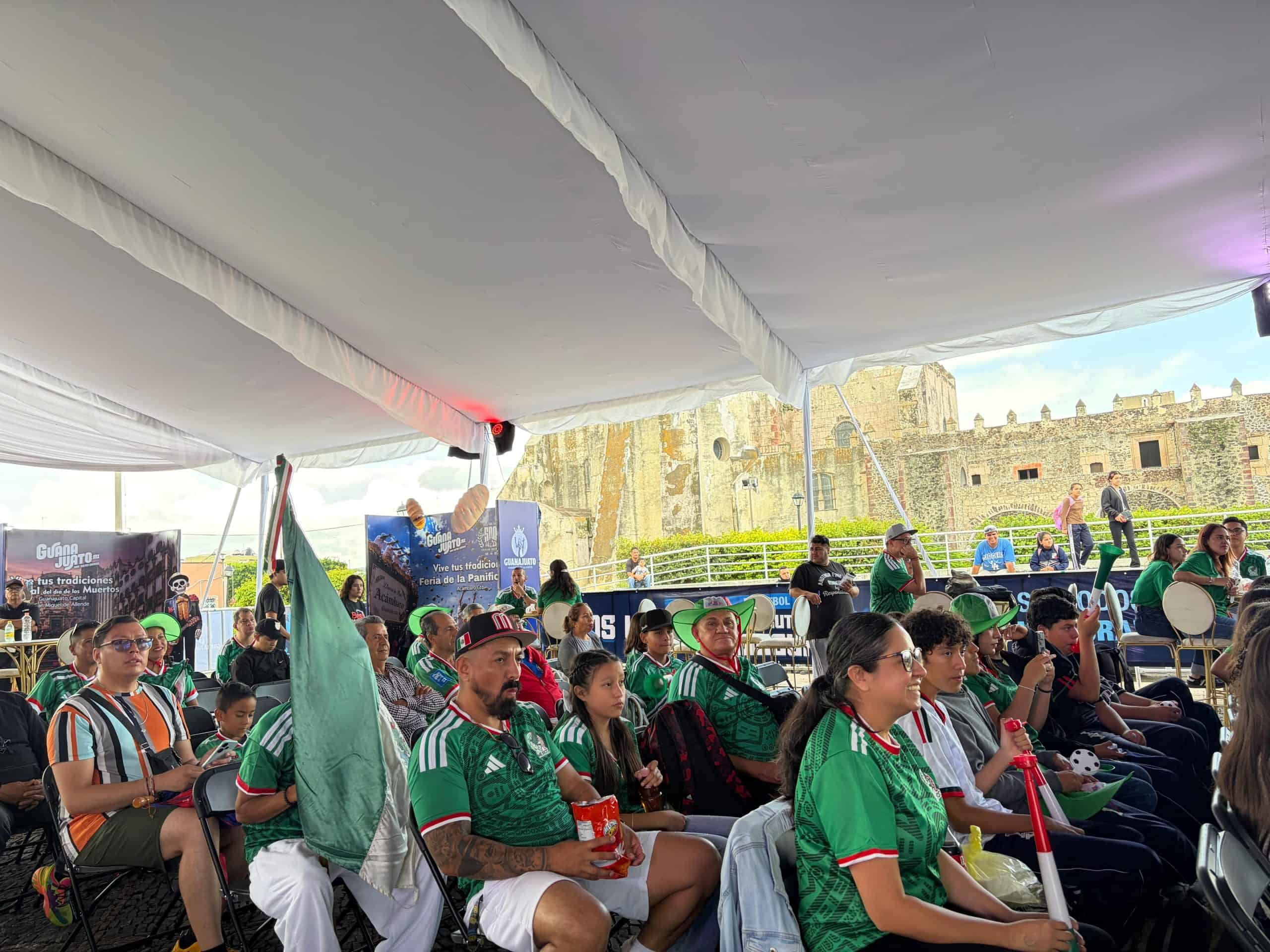 Aficionados de fútbol en la final en Guanajuato con camisetas verdes y banderas.