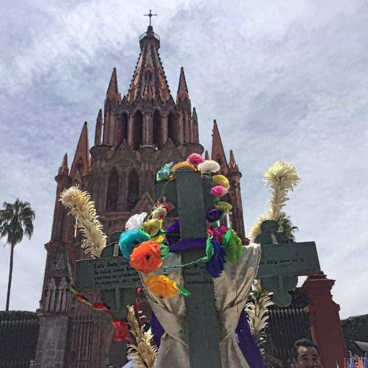 Fachada de la iglesia en San Miguel de Allende con ofrendas florales y decoraciones.