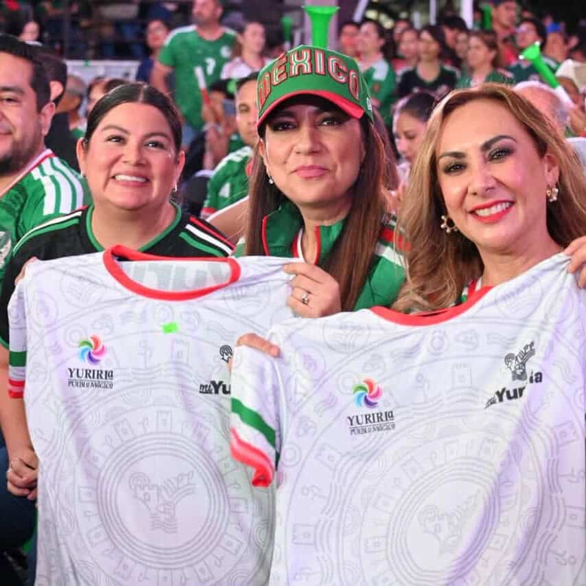 Aficionados mexicanos en un evento deportivo con camisetas y banderas de Yuriria y México.
