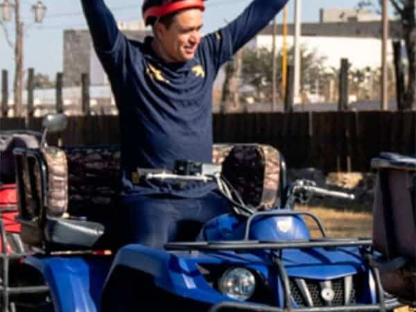 Hombre celebrando con los brazos en alto sobre una cuatrimoto.