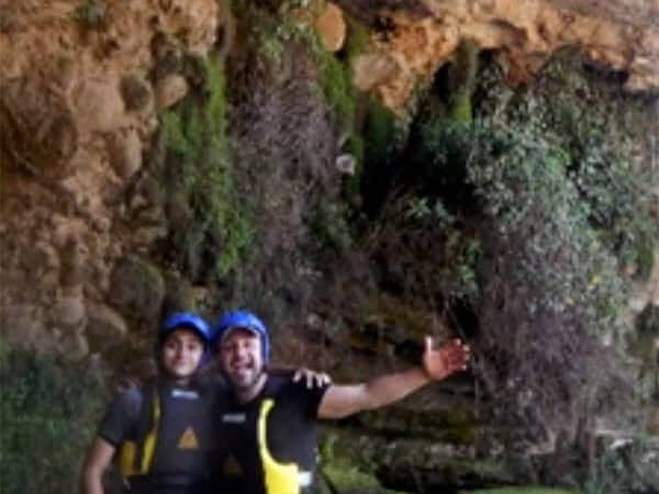 Dos personas con chaleco y casco en una poza bajo una cascada en Tarandacuao.