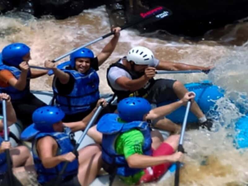 Grupo de personas haciendo rafting en río con equipo de seguridad.
