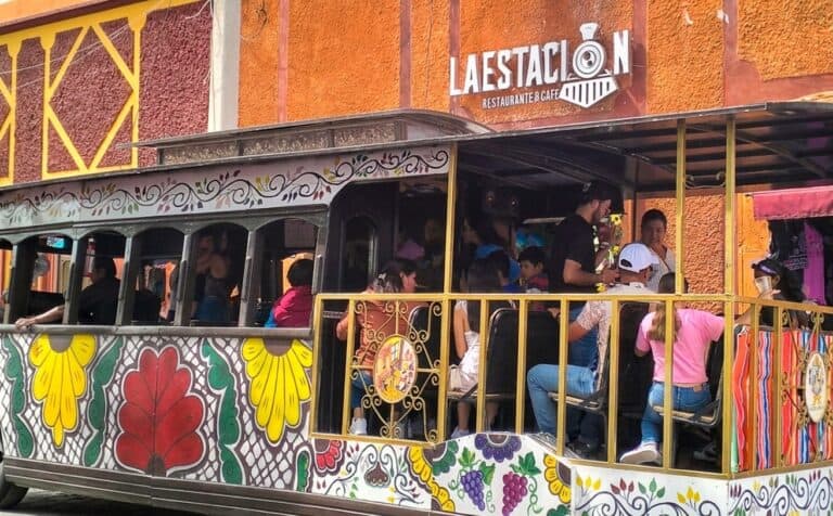 Tranvía turístico en Guanajuato con decoración colorida y pasajeros disfrutando el recorrido.
