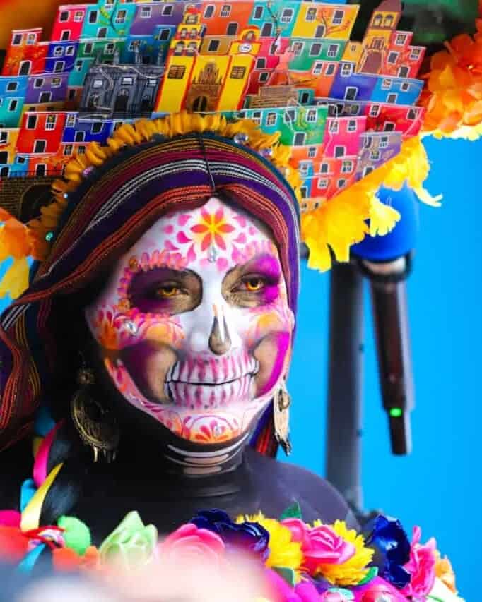 Mujer con maquillaje de calavera y vestuario colorido en Guanajuato durante festividad.