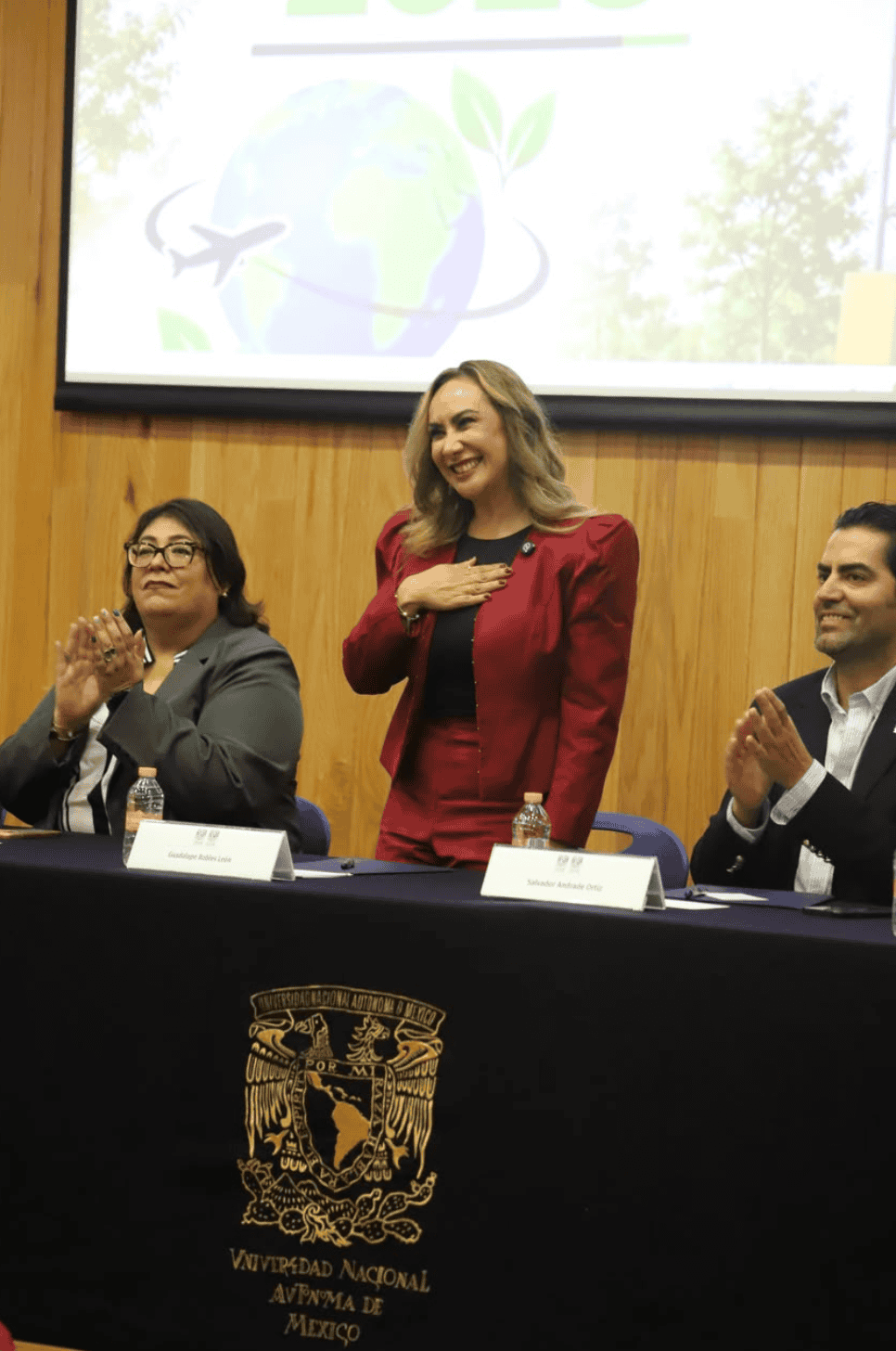 Mujer en evento de turismo en Guanajuato con logo de UNAM y naturaleza de fondo.