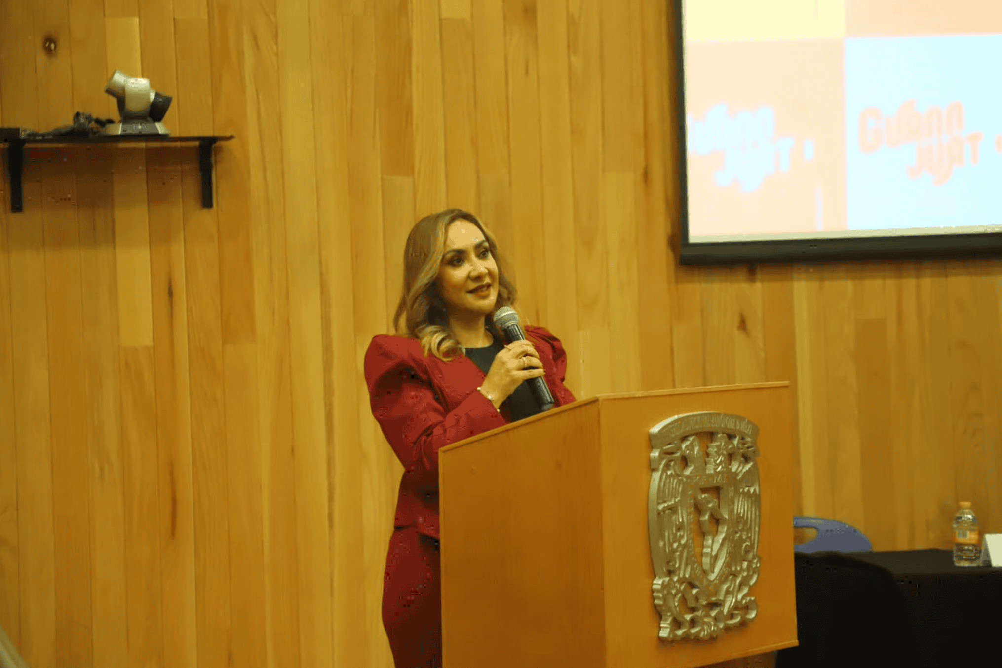 Mujer en evento de turismo en Guanajuato con un podio y pantalla.