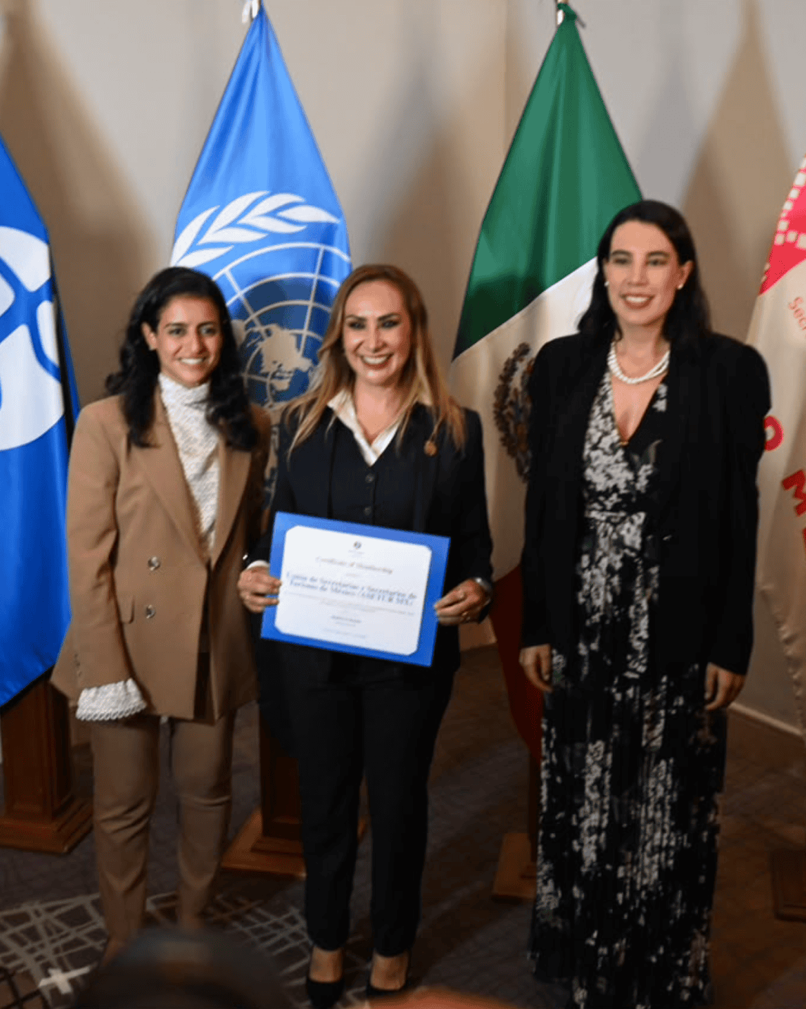 Mujeres en evento de turismo con banderas de ONU y ASETUR en Guanajuato.