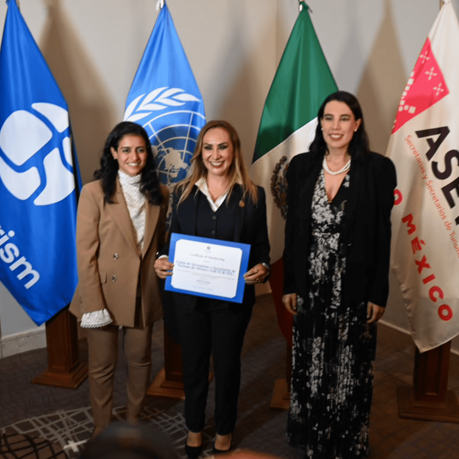 Mujeres en evento de turismo con banderas de ONU y ASETUR en Guanajuato.
