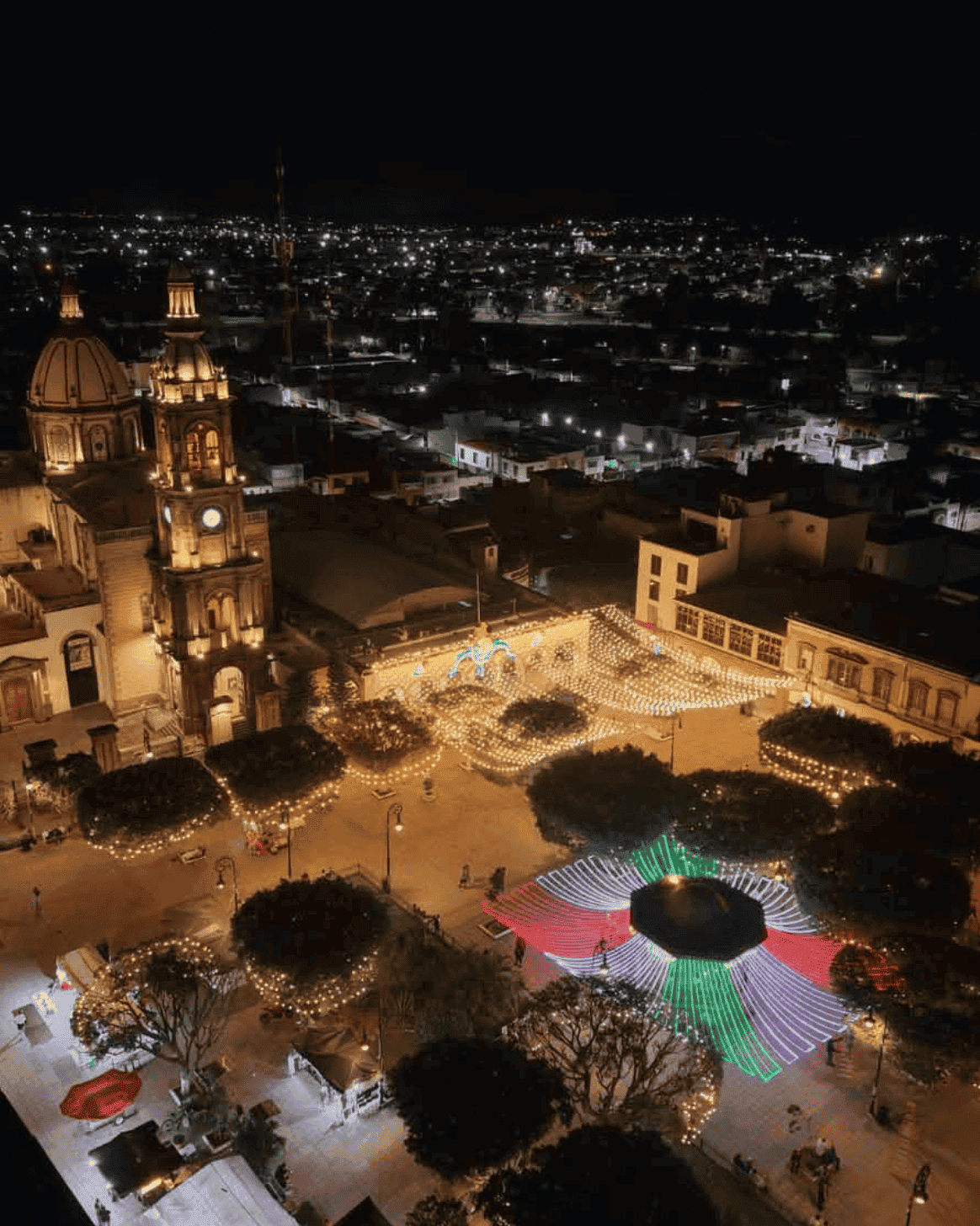 Night view of San Miguel de Allende with lights and festivals in the central square.