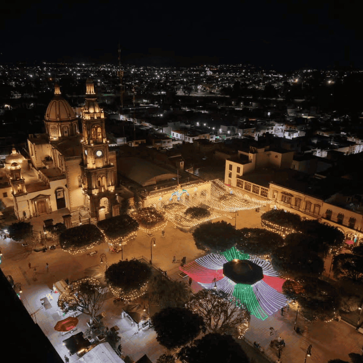 Vista nocturna de San Miguel de Allende con luces y festivales en la plaza central.