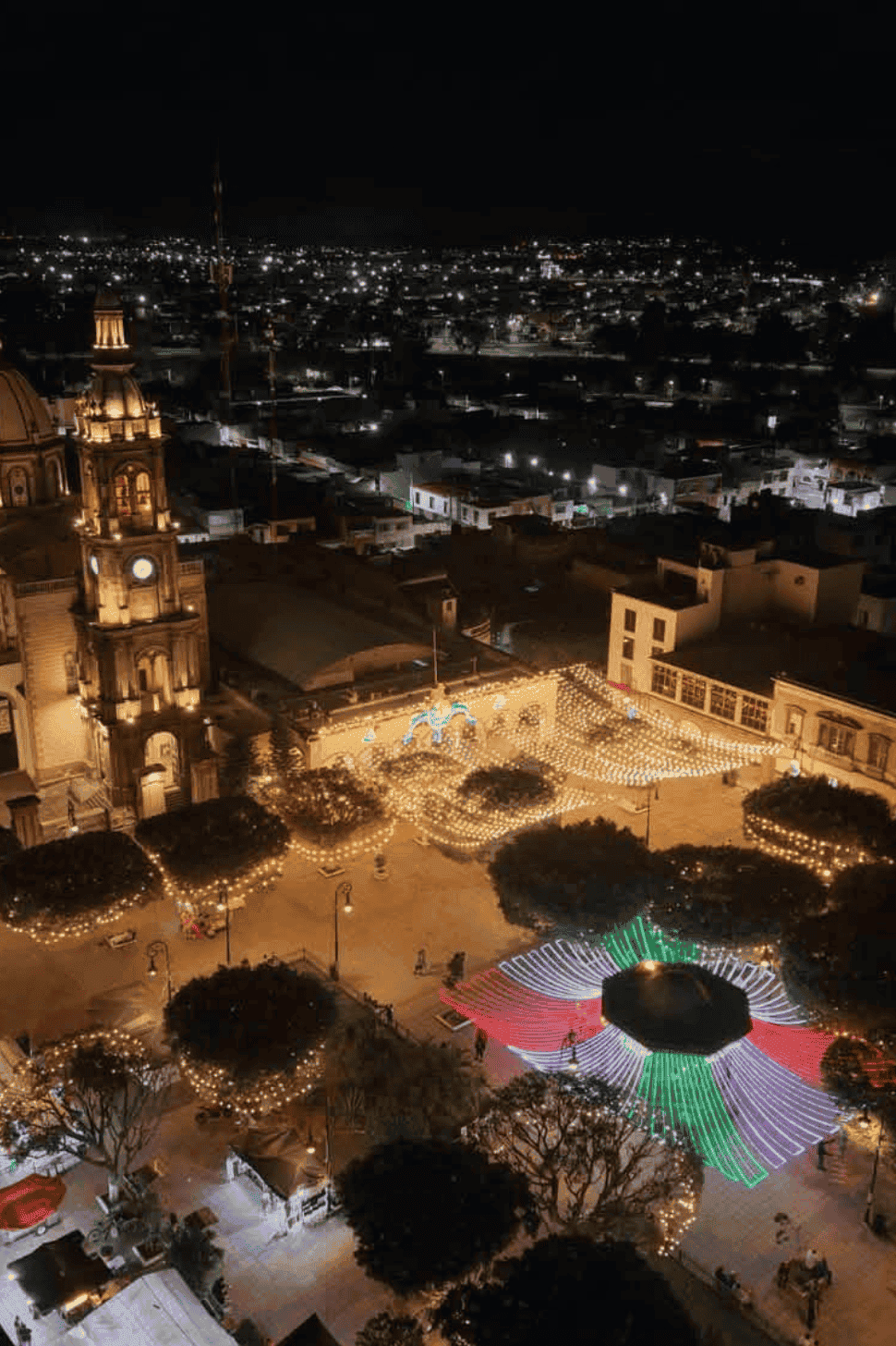 Vista nocturna de San Miguel de Allende con luces y festivales en la plaza central.