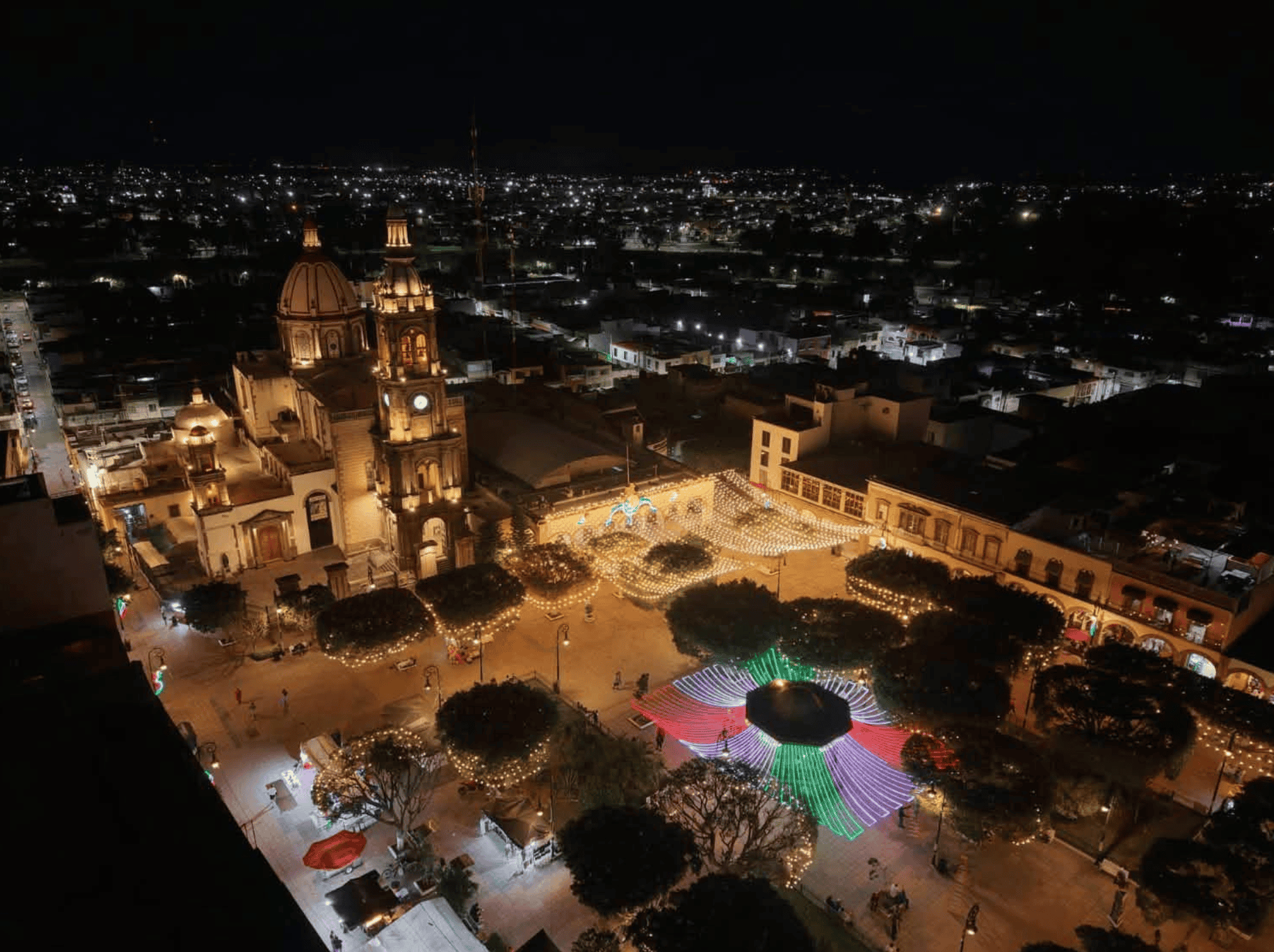 Vista nocturna de San Miguel de Allende con luces y festivales en la plaza central.