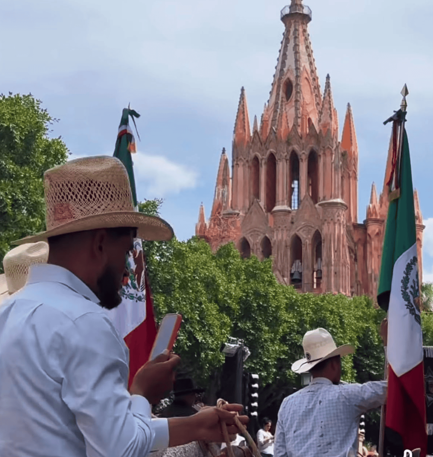 Celebración en San Miguel de Allende con banderas mexicanas y iglesia histórica.
