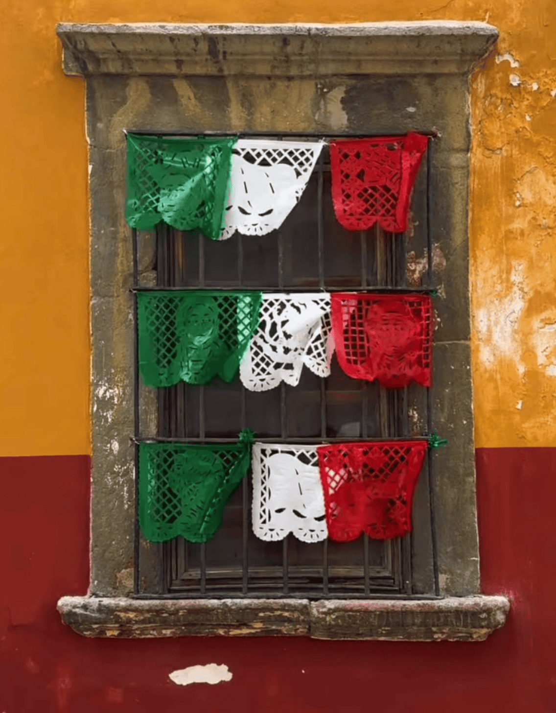 Decoración de papel picado en ventana de color amarillo y rojo en Guanajuato.