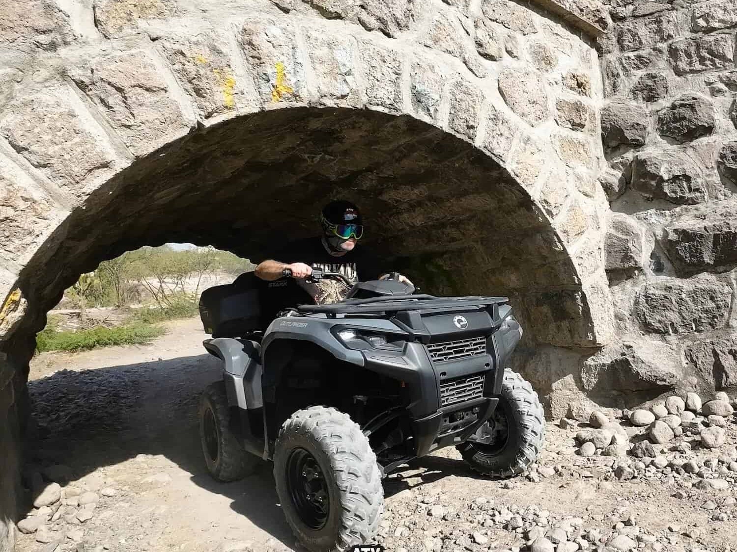 ATV crossing under a stone arch on a rural road near San Miguel de Allende.