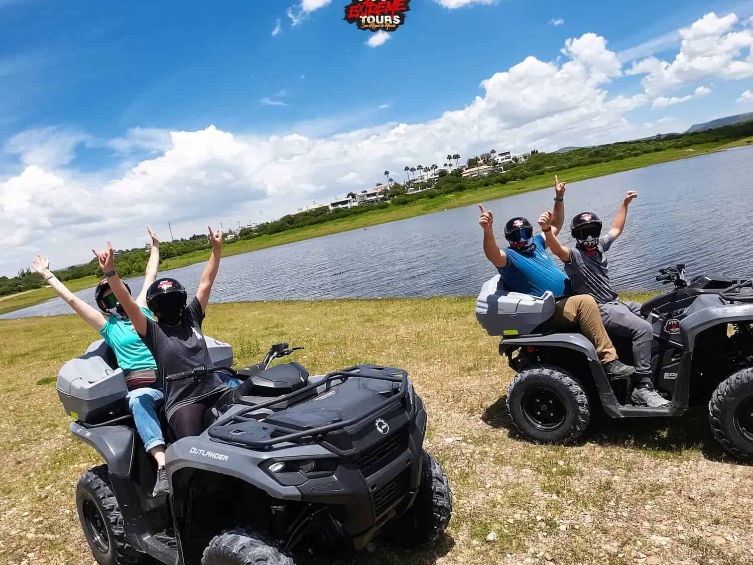 Travelers waving from their ATVs by the shore of the dam.