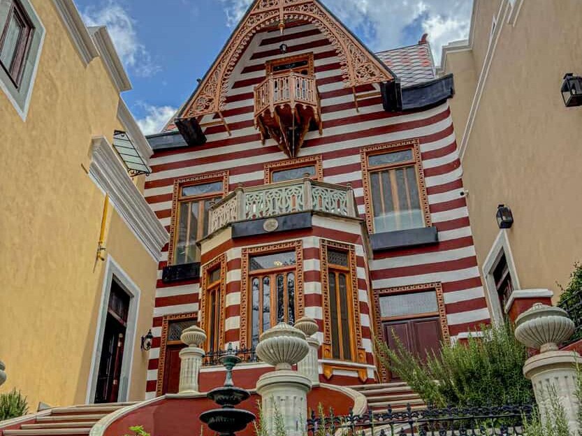 Casona de fachada a rayas rojas y blancas con balcón de madera en el Paseo de la Presa, Guanajuato.