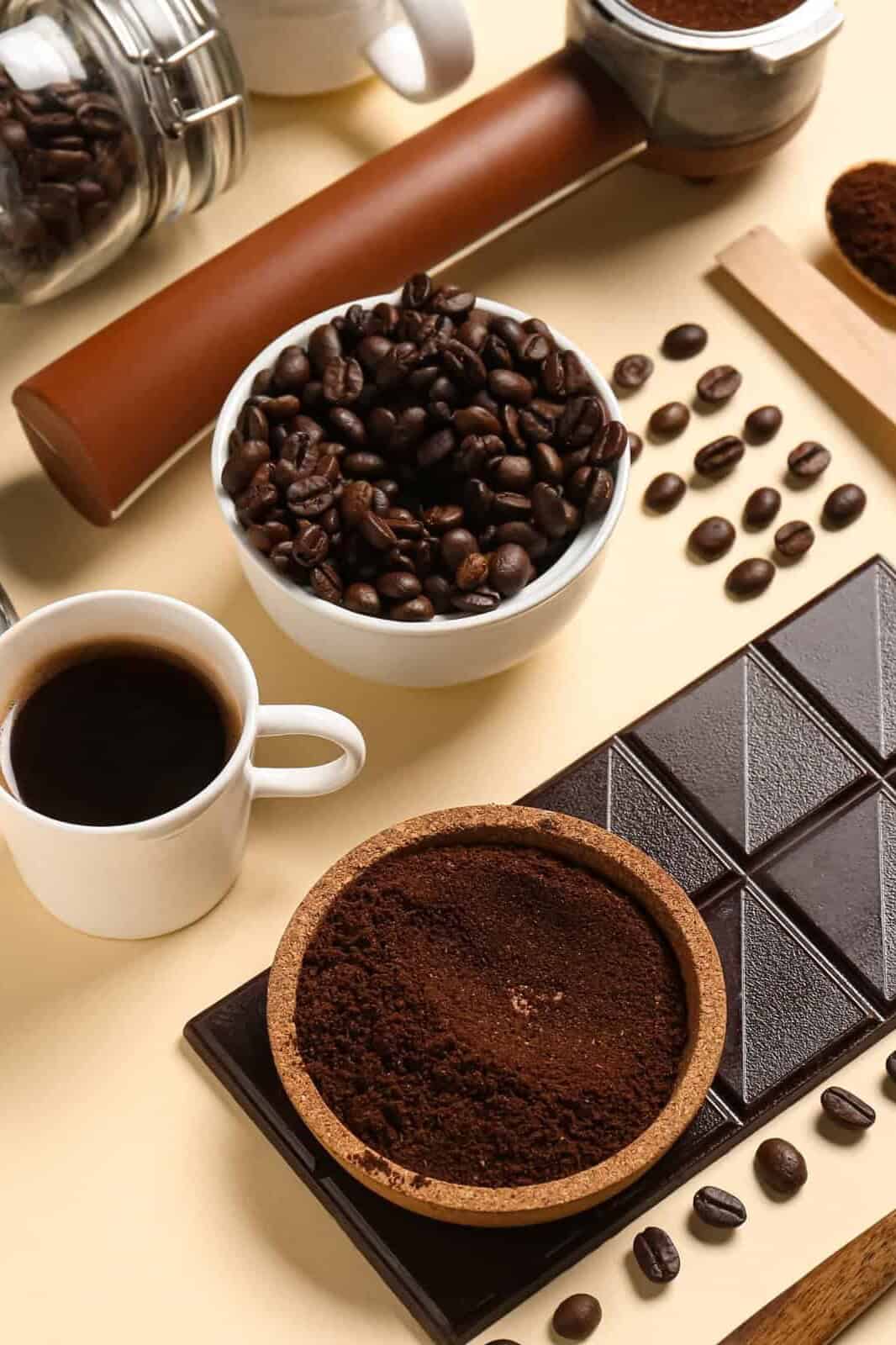 Taza de café con granos, café molido y una tableta de chocolate amargo.