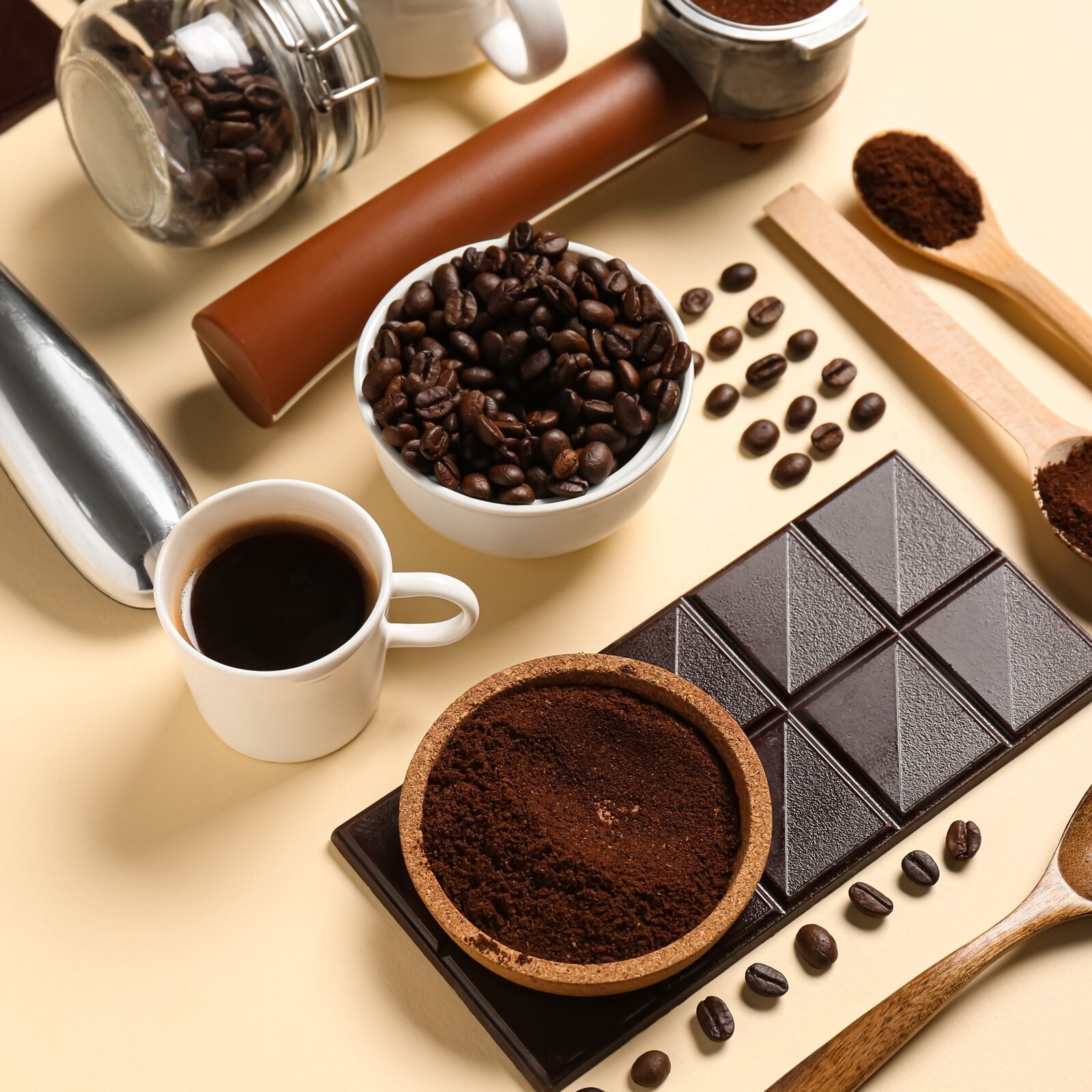 Taza de caf&eacute; con granos, caf&eacute; molido y una tableta de chocolate amargo.