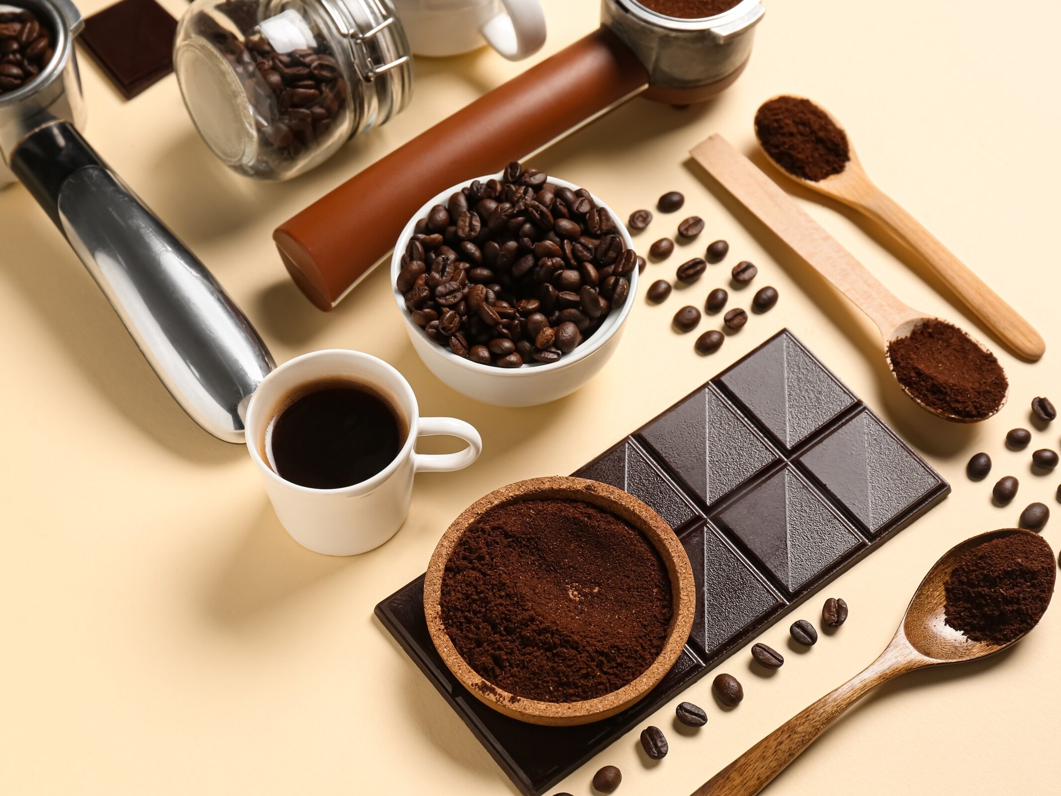 Taza de café con granos, café molido y una tableta de chocolate amargo.