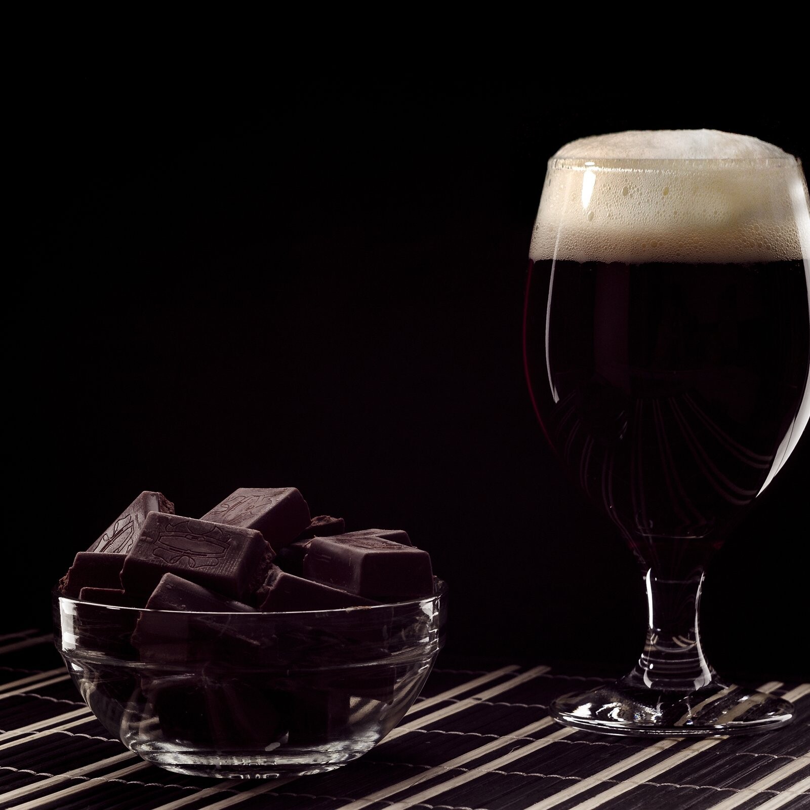 Copa de cerveza oscura junto a un taz&oacute;n con trozos de chocolate amargo.