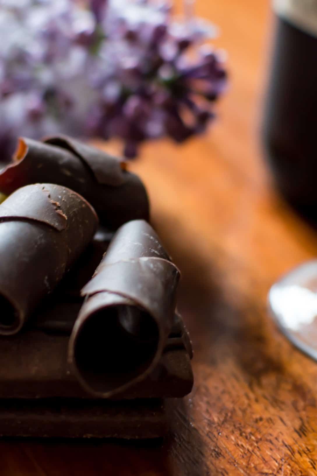 Copa de vino tinto junto a un postre de chocolate con rizos de chocolate amargo y blanco.
