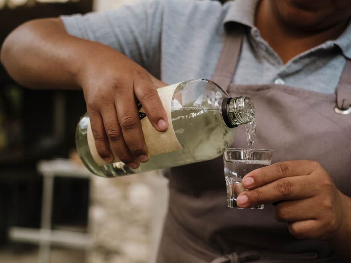Artisan serving artisanal mezcal in a traditional glass.